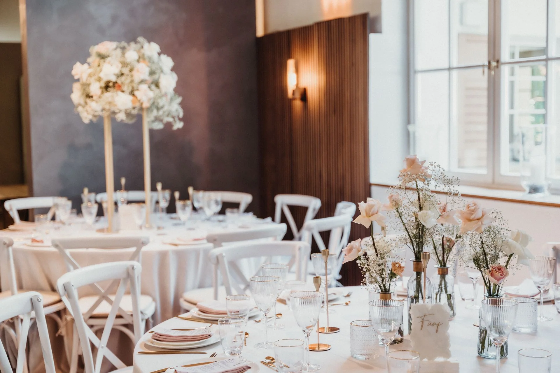 Wedding reception tables with white linens, floral centrepieces and candles